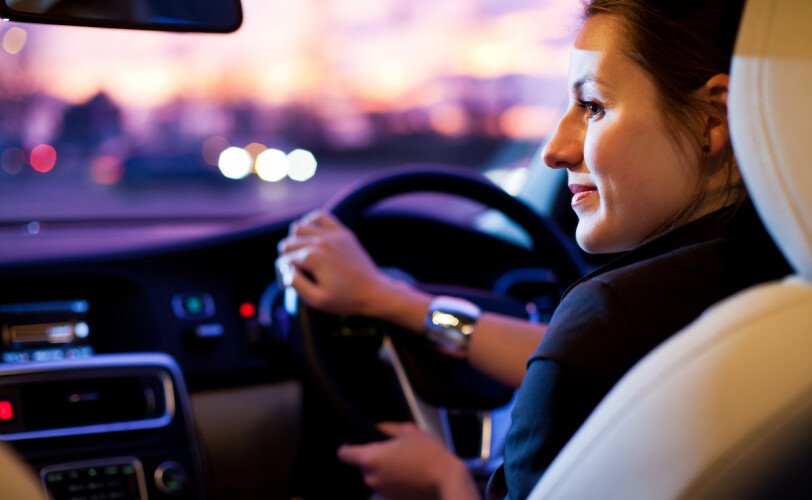 Driving a car at night - pretty, young woman driving her modern car at night in a city (shallow DOF; color toned image)